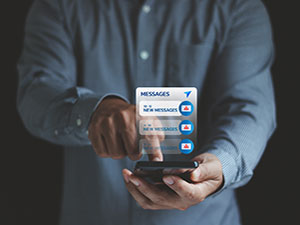 A person using a smartphone with multiple phishing alert messages appearing on the screen, representing the rising threat of smishing attacks and text-based cyber scams.